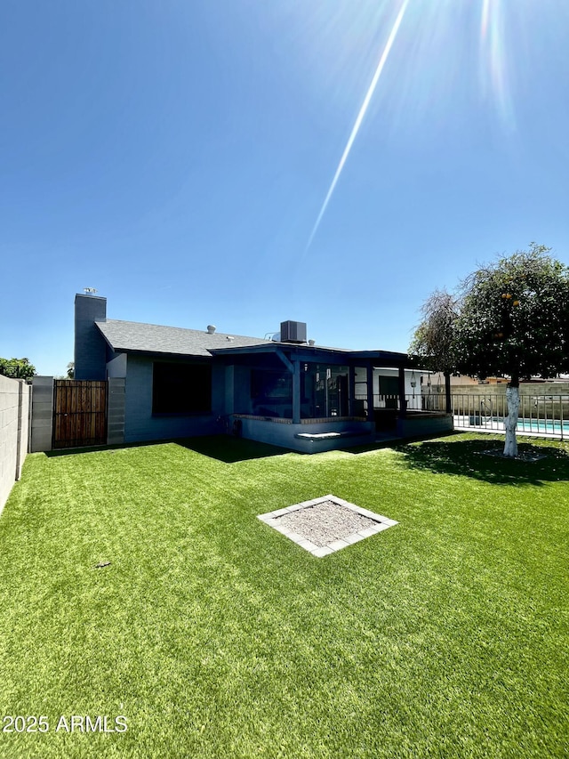 back of property with a pool, central air condition unit, a fenced backyard, and a lawn