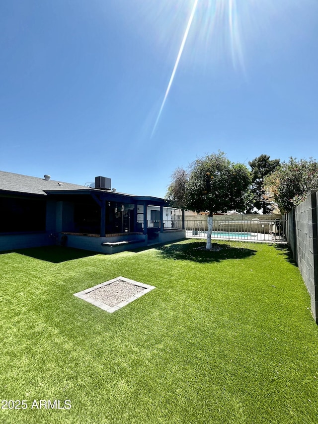 view of yard with fence, a fenced in pool, and cooling unit