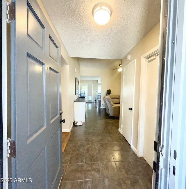 hallway with a textured ceiling and baseboards