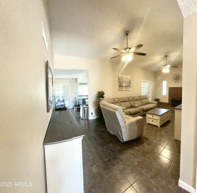living area featuring dark tile patterned flooring, a textured ceiling, a ceiling fan, and lofted ceiling