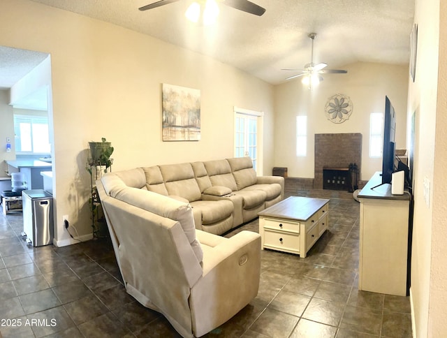 living room featuring dark tile patterned floors, a ceiling fan, a textured ceiling, a fireplace, and vaulted ceiling