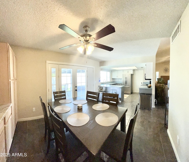 dining space with a textured ceiling, a ceiling fan, visible vents, dark tile patterned floors, and french doors