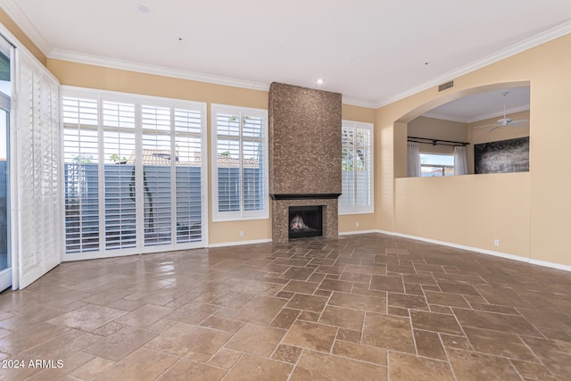 unfurnished living room featuring a large fireplace, ceiling fan, and ornamental molding