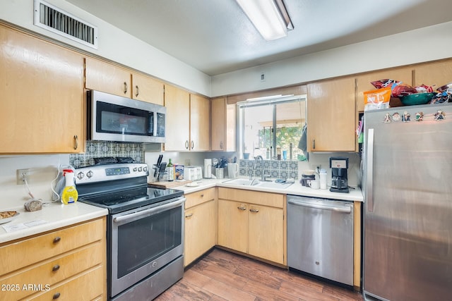 kitchen featuring stainless steel appliances, sink, light brown cabinets, and dark hardwood / wood-style flooring