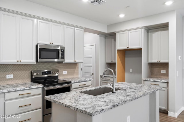 1823 E Chelsea Ln Unit 106, Gilbert, AZ 85295 - kitchen with stainless steel appliances, a sink, tasteful backsplash, a center island with sink, and light stone countertops