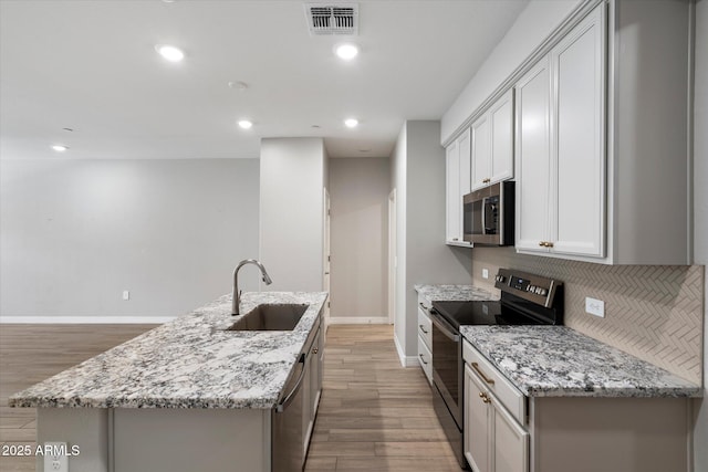 1823 E Chelsea Ln Unit 106, Gilbert, AZ 85295 - kitchen featuring stainless steel appliances, a sink, a kitchen island with sink, baseboards, and light wood-style flooring