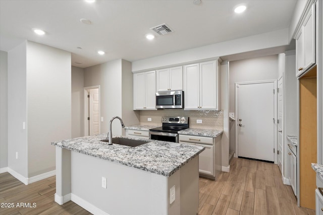 1823 E Chelsea Ln Unit 106, Gilbert, AZ 85295 - kitchen featuring stainless steel appliances, a sink, light wood-style flooring, a center island with sink, and decorative backsplash