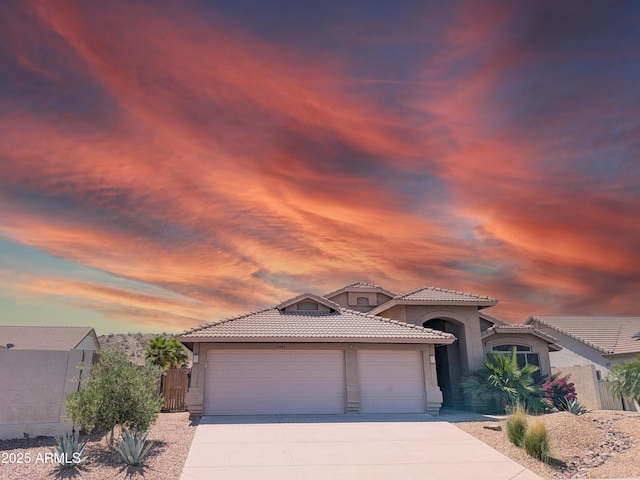 11424 S Obispo Dr, Goodyear, AZ 85338 - mediterranean / spanish house featuring stucco siding, a tile roof, an attached garage, driveway, and fence