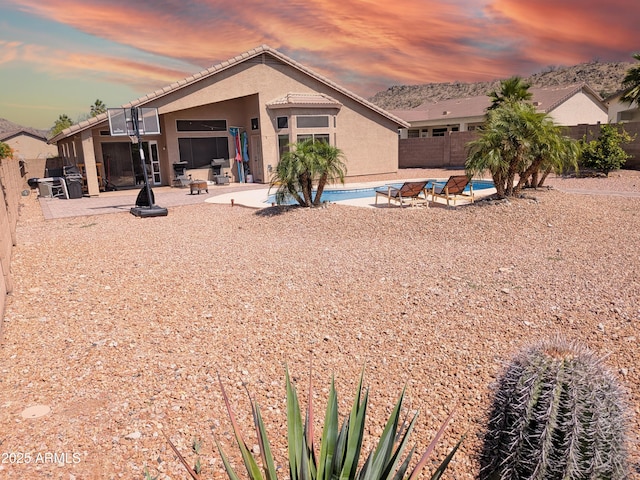 11424 S Obispo Dr, Goodyear, AZ 85338 - back of house at dusk featuring stucco siding, a patio area, a fenced backyard, and a tiled roof