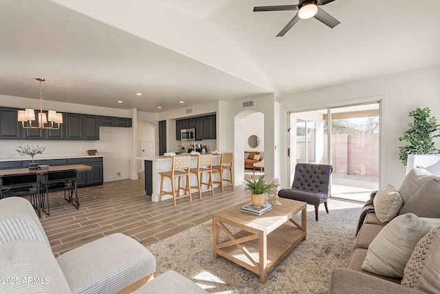 living room featuring hardwood / wood-style floors, ceiling fan with notable chandelier, and lofted ceiling