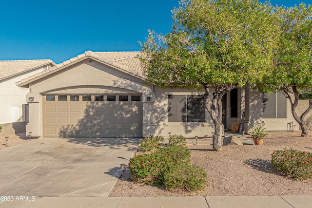 view of front facade with a garage, concrete driveway, a tile roof, and stucco siding