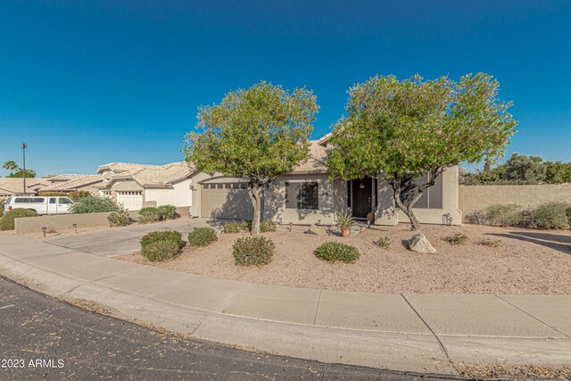 view of front facade featuring a garage, concrete driveway, a tiled roof, and stucco siding