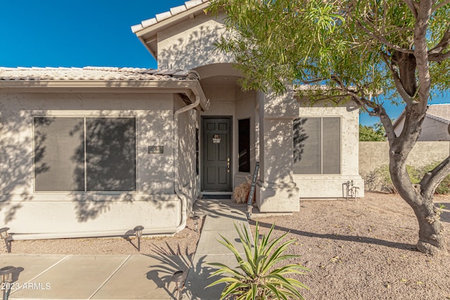 doorway to property featuring a tiled roof and stucco siding