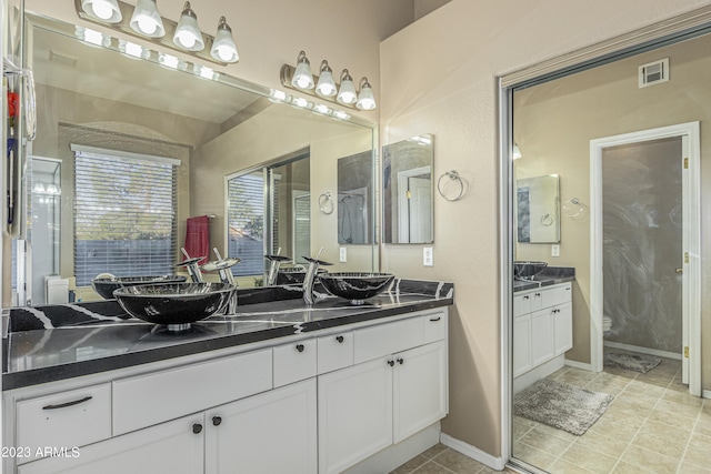 full bath featuring double vanity, baseboards, visible vents, and a sink