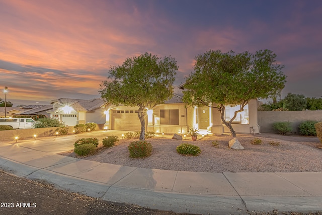 view of front facade featuring a garage, driveway, fence, and stucco siding