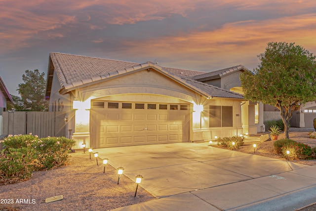 mediterranean / spanish-style home with concrete driveway, a tile roof, an attached garage, fence, and stucco siding