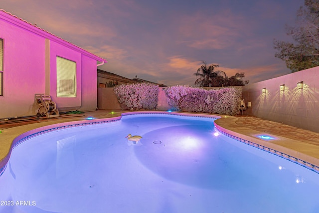 pool at dusk featuring a fenced backyard and a fenced in pool