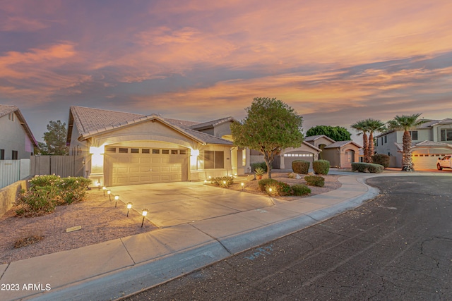 view of front of property featuring a tile roof, stucco siding, an attached garage, fence, and driveway