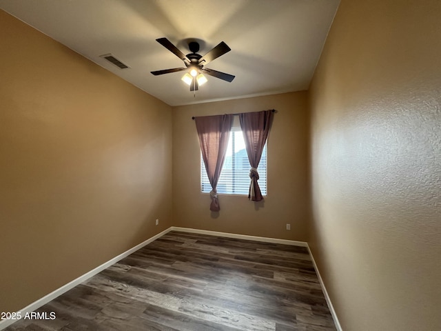 unfurnished room featuring ceiling fan, dark wood-style flooring, visible vents, and baseboards