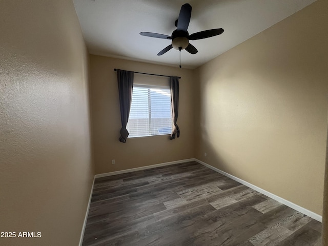 spare room featuring ceiling fan, dark wood-style flooring, and baseboards