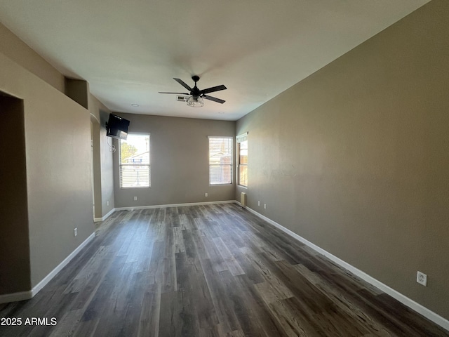 spare room with ceiling fan, baseboards, and dark wood-type flooring