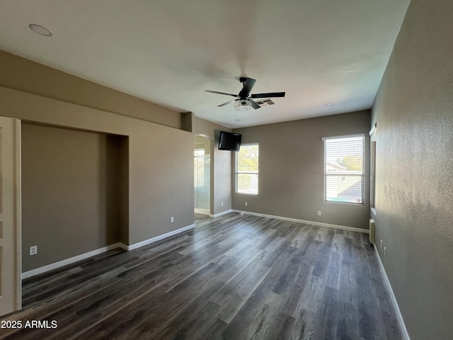 spare room featuring ceiling fan, dark wood-type flooring, visible vents, and baseboards