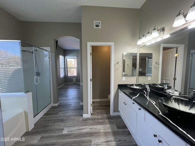 full bathroom featuring visible vents, toilet, a stall shower, a sink, and wood finished floors