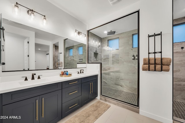 bathroom with a tile shower, tile patterned flooring, vanity, and a healthy amount of sunlight