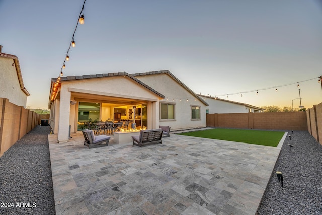 back house at dusk featuring a patio area and a yard