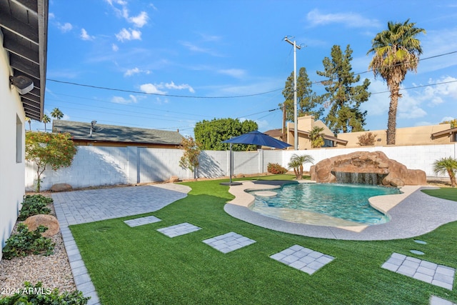 view of swimming pool featuring a yard, pool water feature, and a patio area