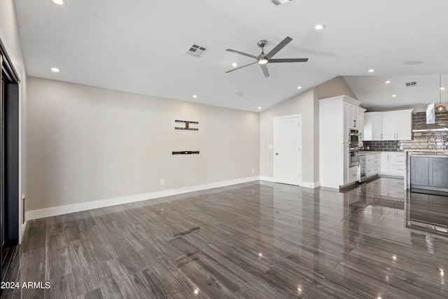 unfurnished living room with vaulted ceiling, ceiling fan, dark wood-type flooring, and sink