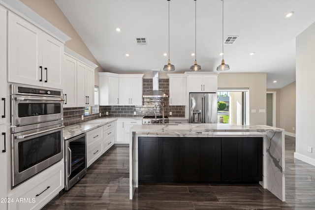 kitchen featuring a center island with sink, wall chimney exhaust hood, stainless steel appliances, and beverage cooler