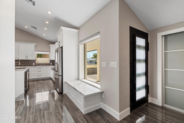 interior space featuring white cabinets, stainless steel appliances, vaulted ceiling, and dark hardwood / wood-style floors