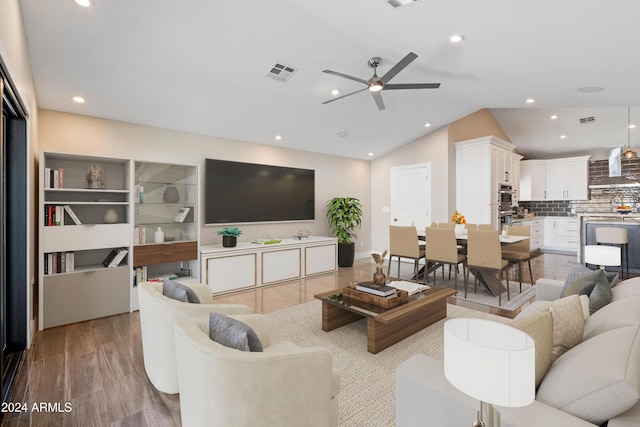 living room featuring ceiling fan, light wood-type flooring, and lofted ceiling