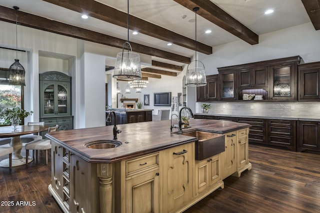 kitchen with tasteful backsplash, sink, dark hardwood / wood-style floors, and an island with sink