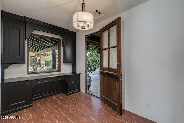 doorway featuring hardwood / wood-style floors, built in desk, and a chandelier