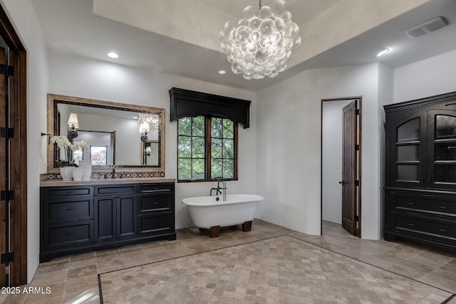 bathroom featuring an inviting chandelier, vanity, and a washtub