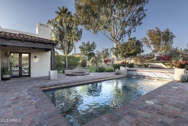 view of swimming pool with pool water feature, a patio, and a fire pit