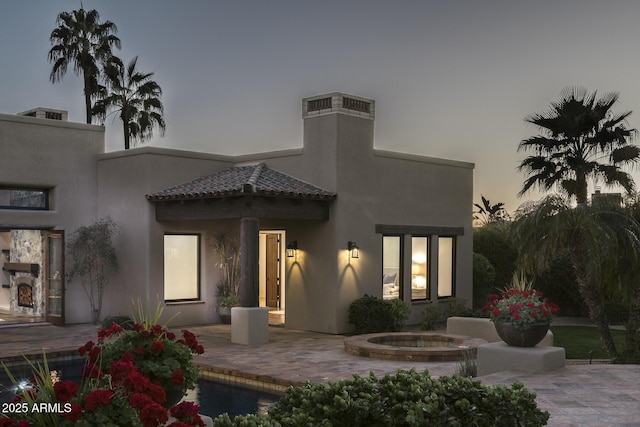 back house at dusk featuring a patio area