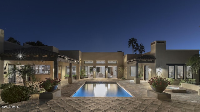 pool at night with a patio and ceiling fan