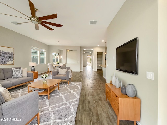 living room with ceiling fan with notable chandelier and dark hardwood / wood-style floors