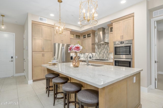 kitchen with tasteful backsplash, wall chimney range hood, stainless steel appliances, a large island, and light brown cabinetry