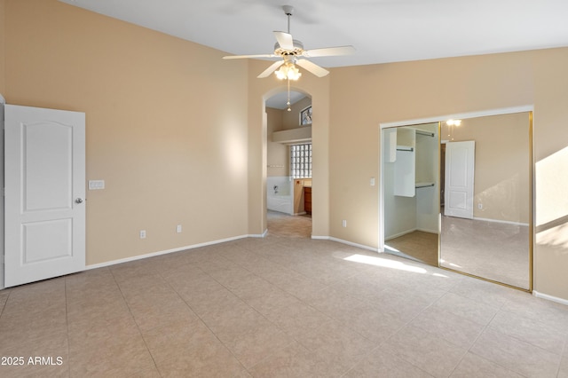 unfurnished bedroom with ceiling fan, light tile patterned floors, lofted ceiling, and a closet