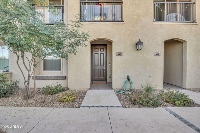 property entrance featuring a balcony and stucco siding