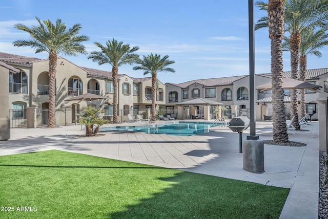 pool featuring a patio, a lawn, and a residential view