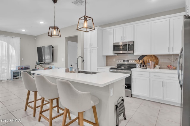 kitchen featuring pendant lighting, light countertops, appliances with stainless steel finishes, a sink, and an island with sink