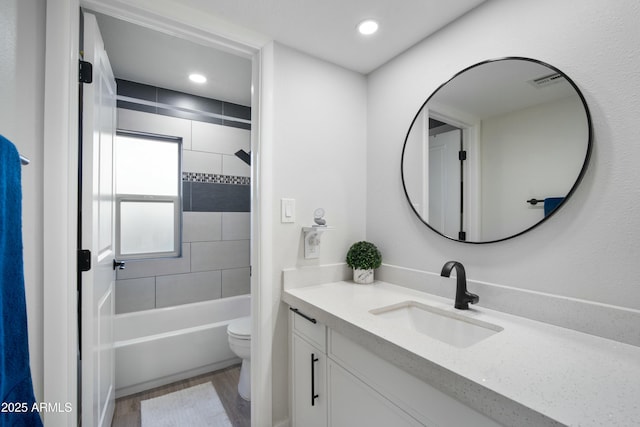 full bathroom featuring toilet, tiled shower / bath, wood-type flooring, and vanity