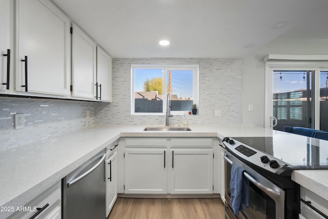 kitchen with tasteful backsplash, sink, light hardwood / wood-style flooring, appliances with stainless steel finishes, and white cabinets