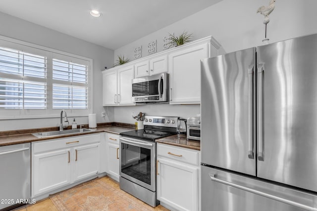 kitchen with light tile patterned floors, stainless steel appliances, sink, and white cabinets