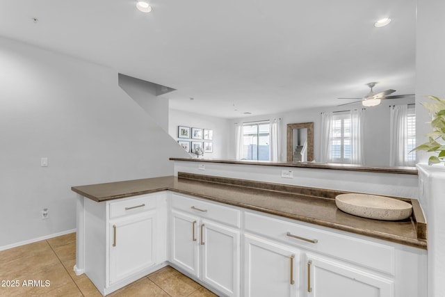 kitchen with light tile patterned floors, white cabinets, ceiling fan, and kitchen peninsula